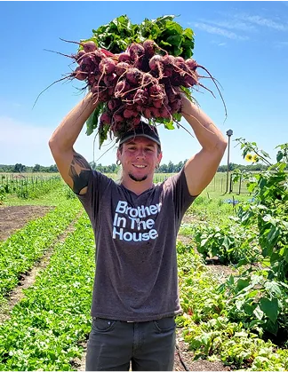 A young farmer holding a bushel of onions over his head.