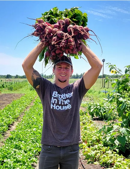 A young farmer holding a bushel of onions over his head.